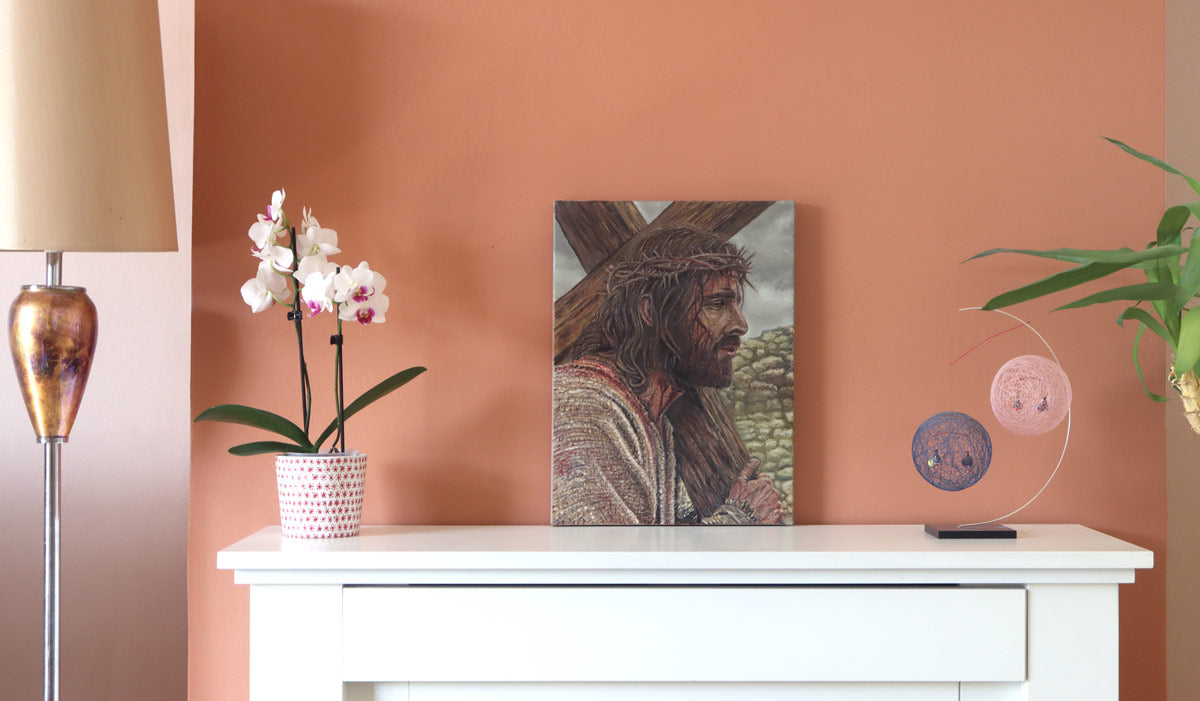 A photograph of a small oil painting in a real life situation on a mantlepiece, the painting is of Jesus Christ bearing the cross, by Martin Buckwell