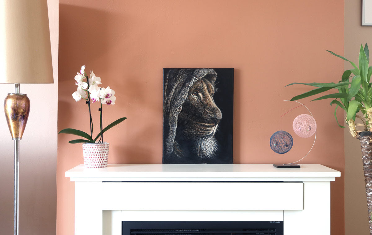 A real photograph of the original Lion of Judah oil painting displayed on a mantlepiece, shown for context of size