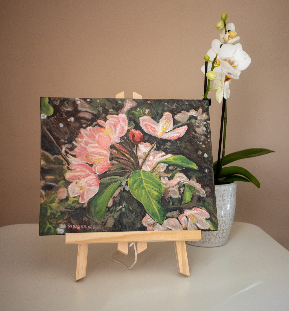 A photograph of a small original oil canvas board painting on a tabletop easel, of springtime blossom in a fruit tree, United Kingdom from Martin Buckwell